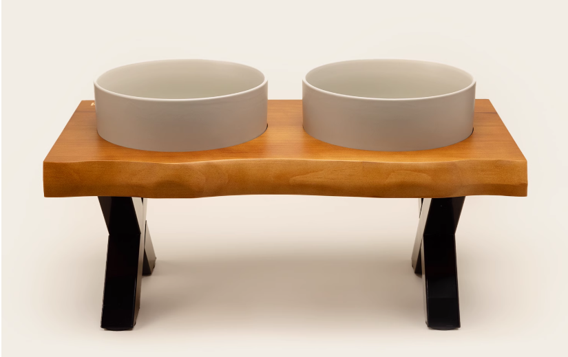 Wooden pet feeder with two ceramic bowls on a white background