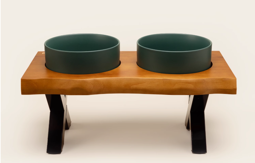 Wooden pet feeder with two green bowls on a white background