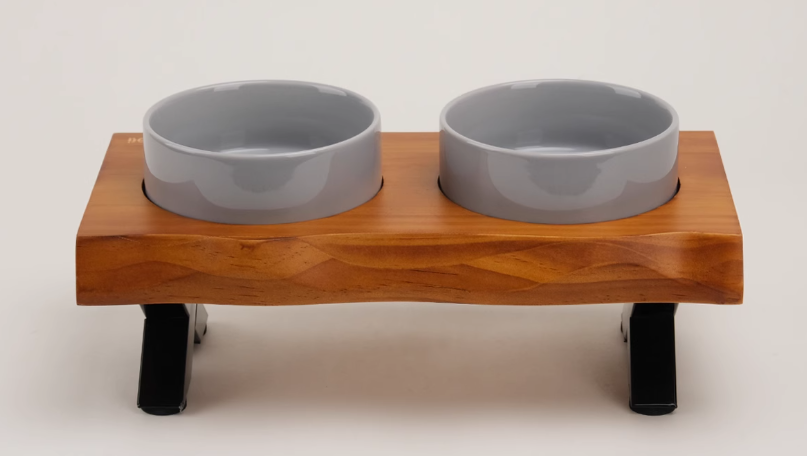 Wooden pet feeder with two gray bowls on a white background