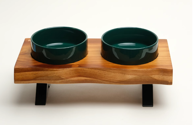 Wooden pet feeder with two green bowls on a white background