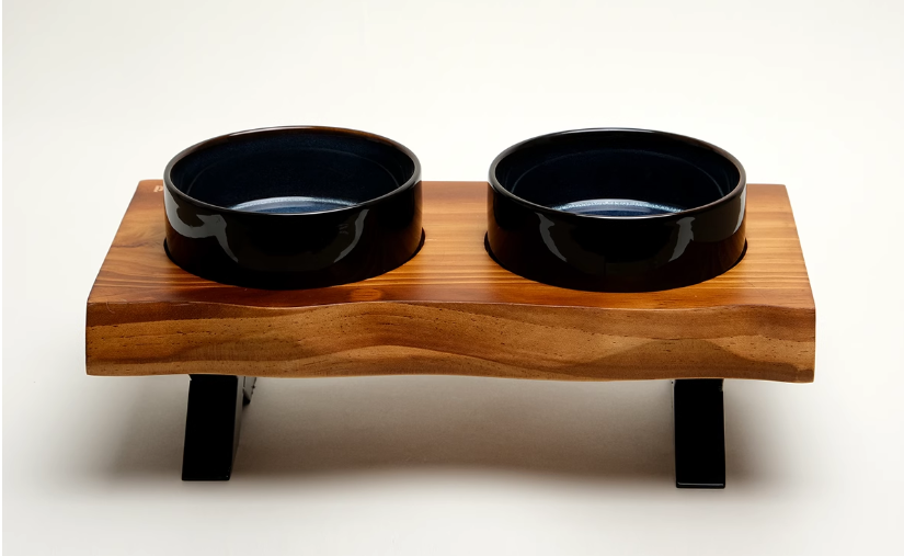 Wooden pet feeder with two black bowls on a white background