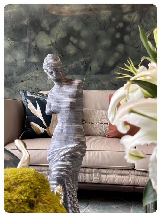 Decorative statue in a living room setting with a sofa and flowers.