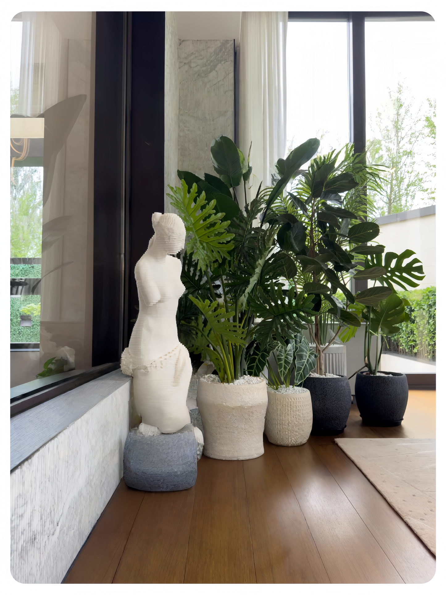 Decorative statue and plants in a modern indoor setting with large windows.
