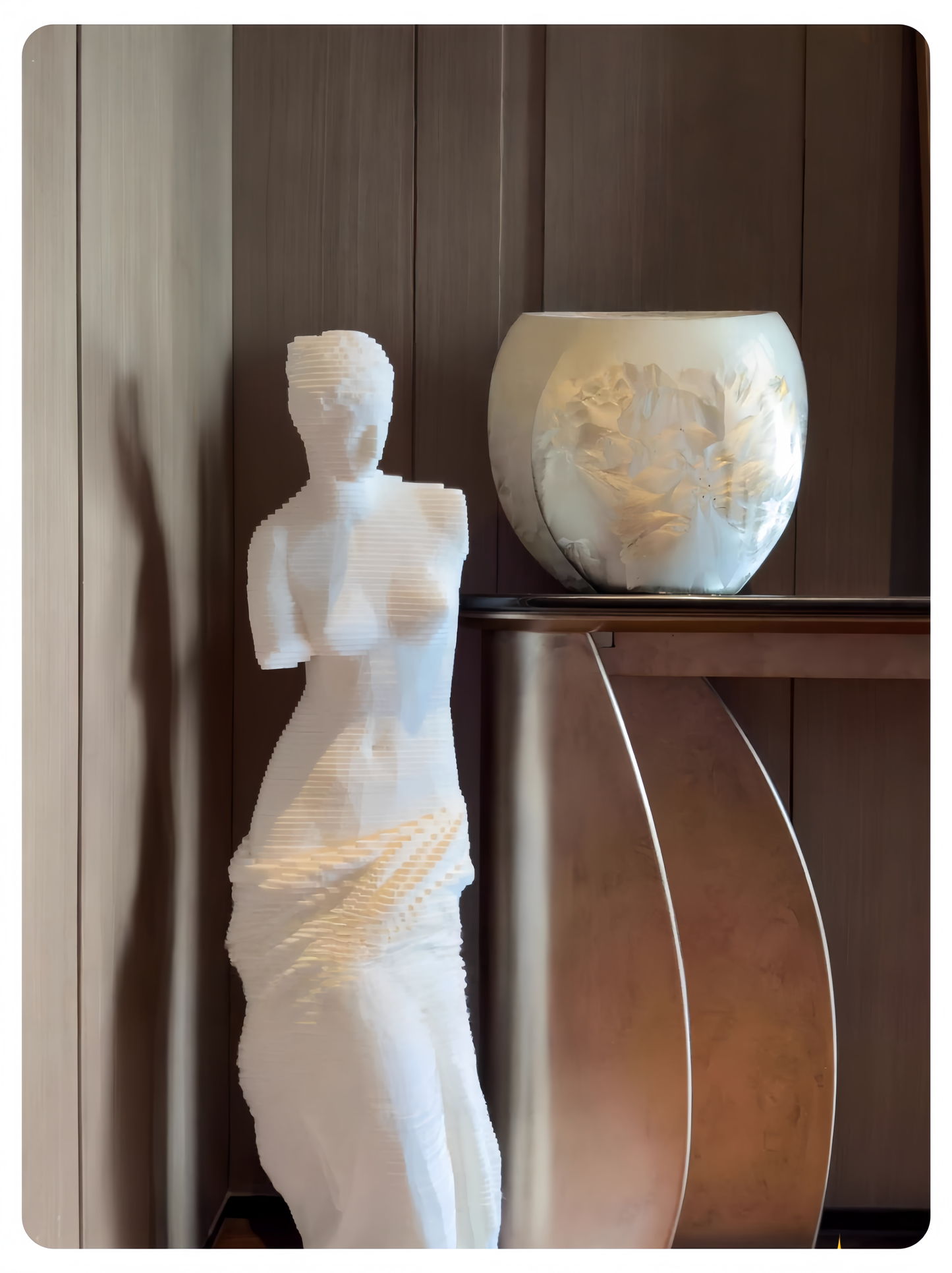 White sculpture and decorative vase against a wooden wall