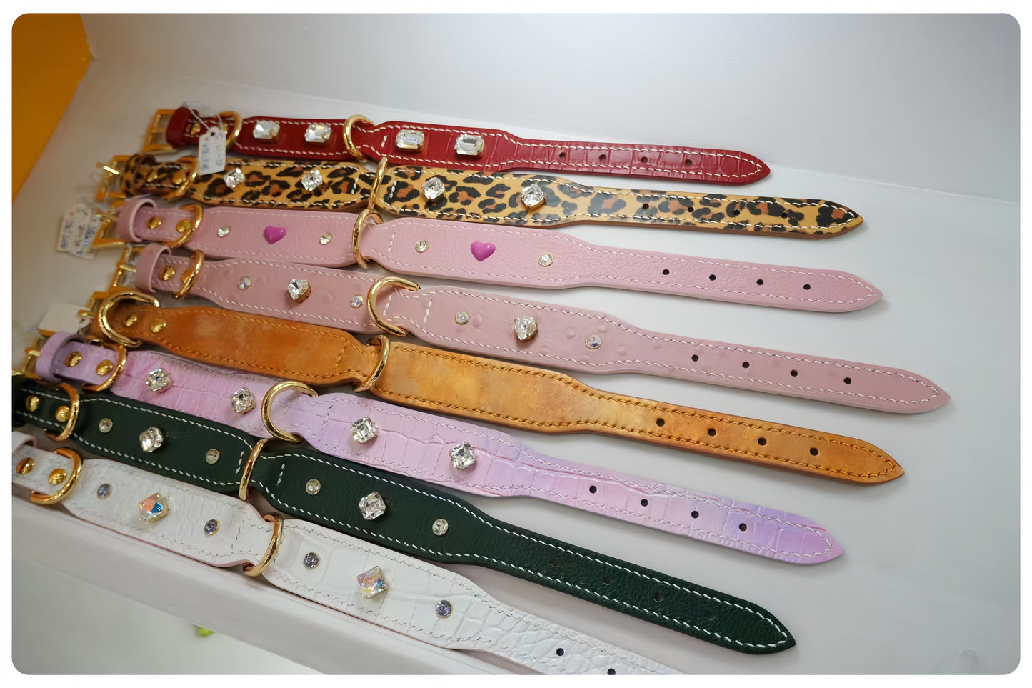 Collection of colorful dog collars with decorative elements on a white surface