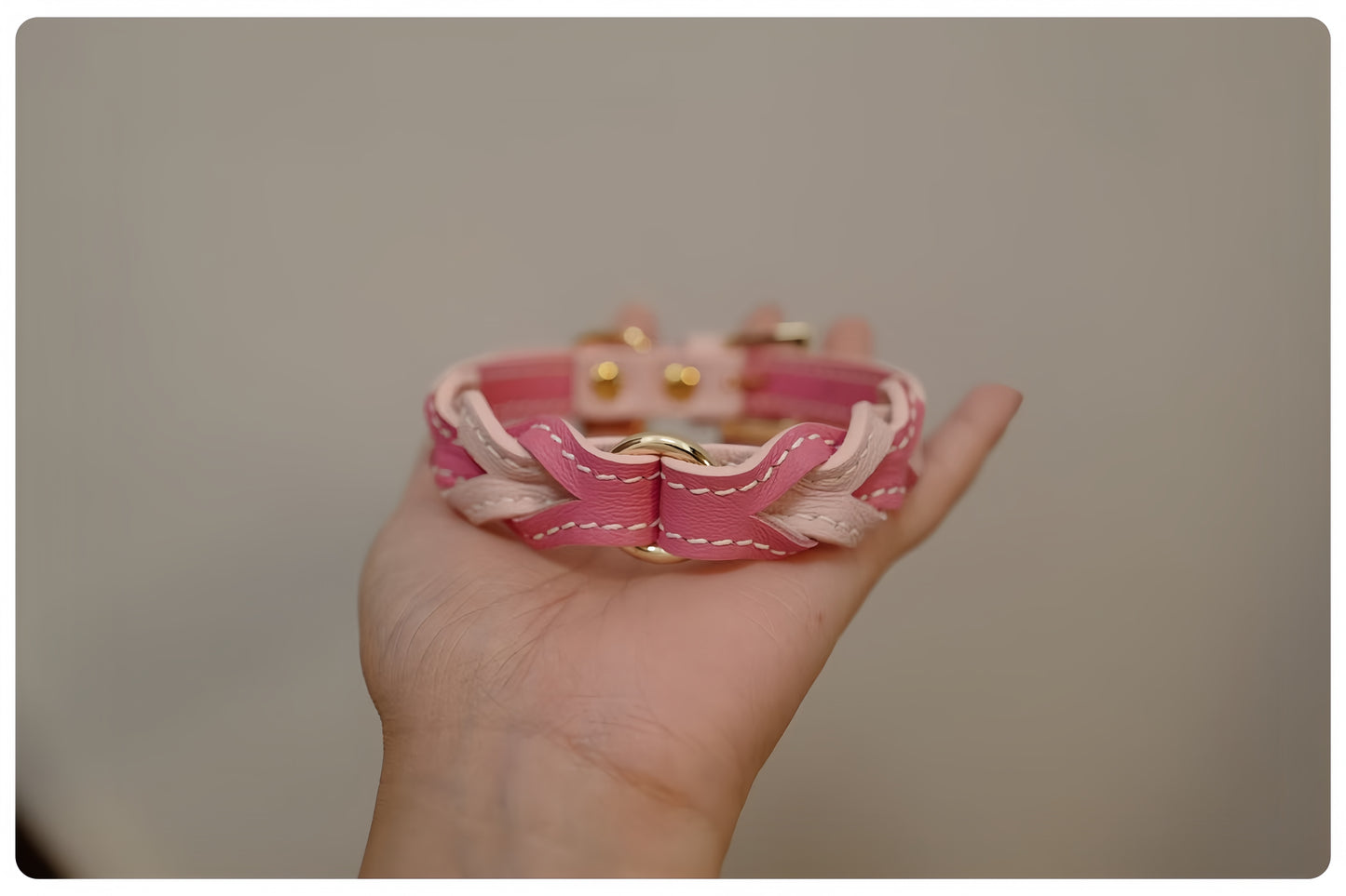 Hand holding a pink braided bracelet against a plain background