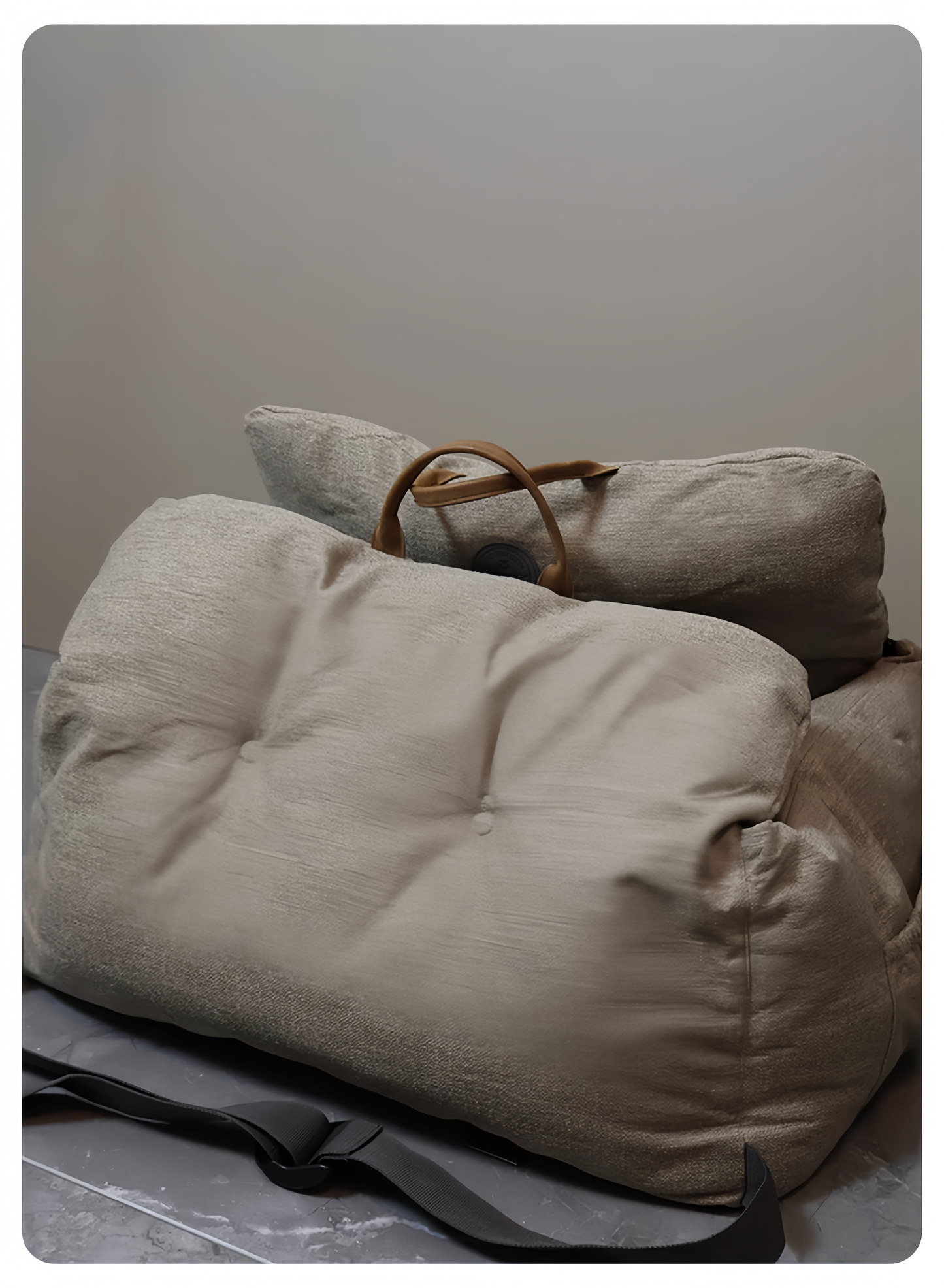Two beige bean bags with a brown strap on a gray surface against a plain background