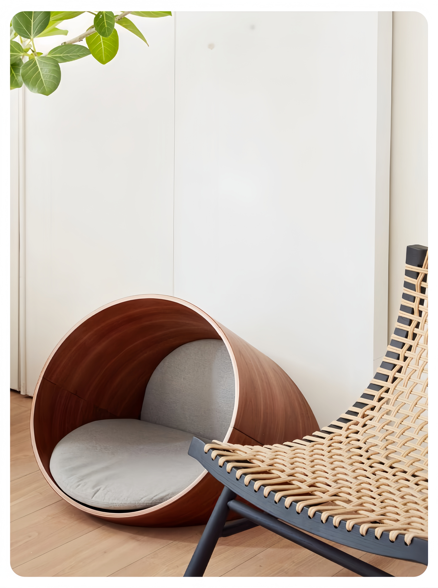 Wooden pet den with white cushion next to a wicker chair indoors.