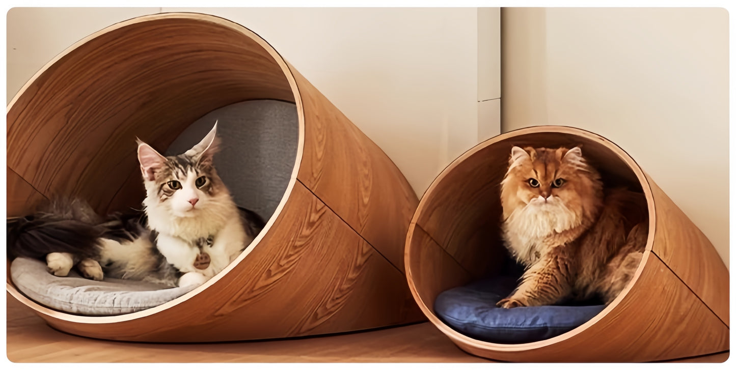 Two cats inside wooden tube-shaped pet beds on a light wood floor.