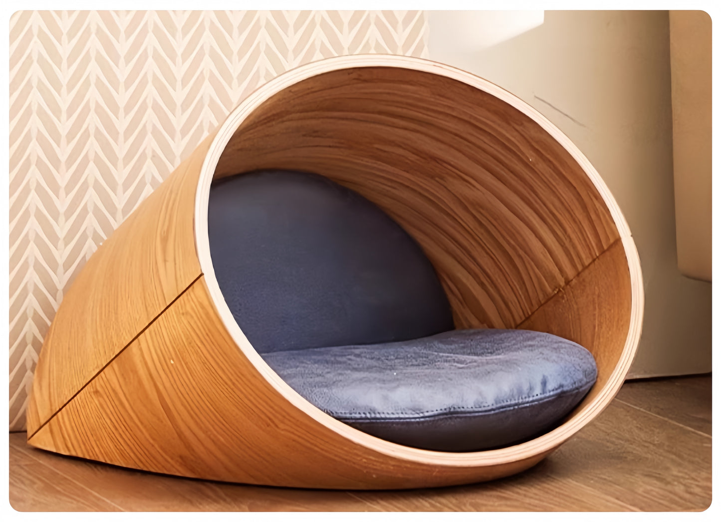 Wooden pet bed with a blue cushion on a wooden floor.