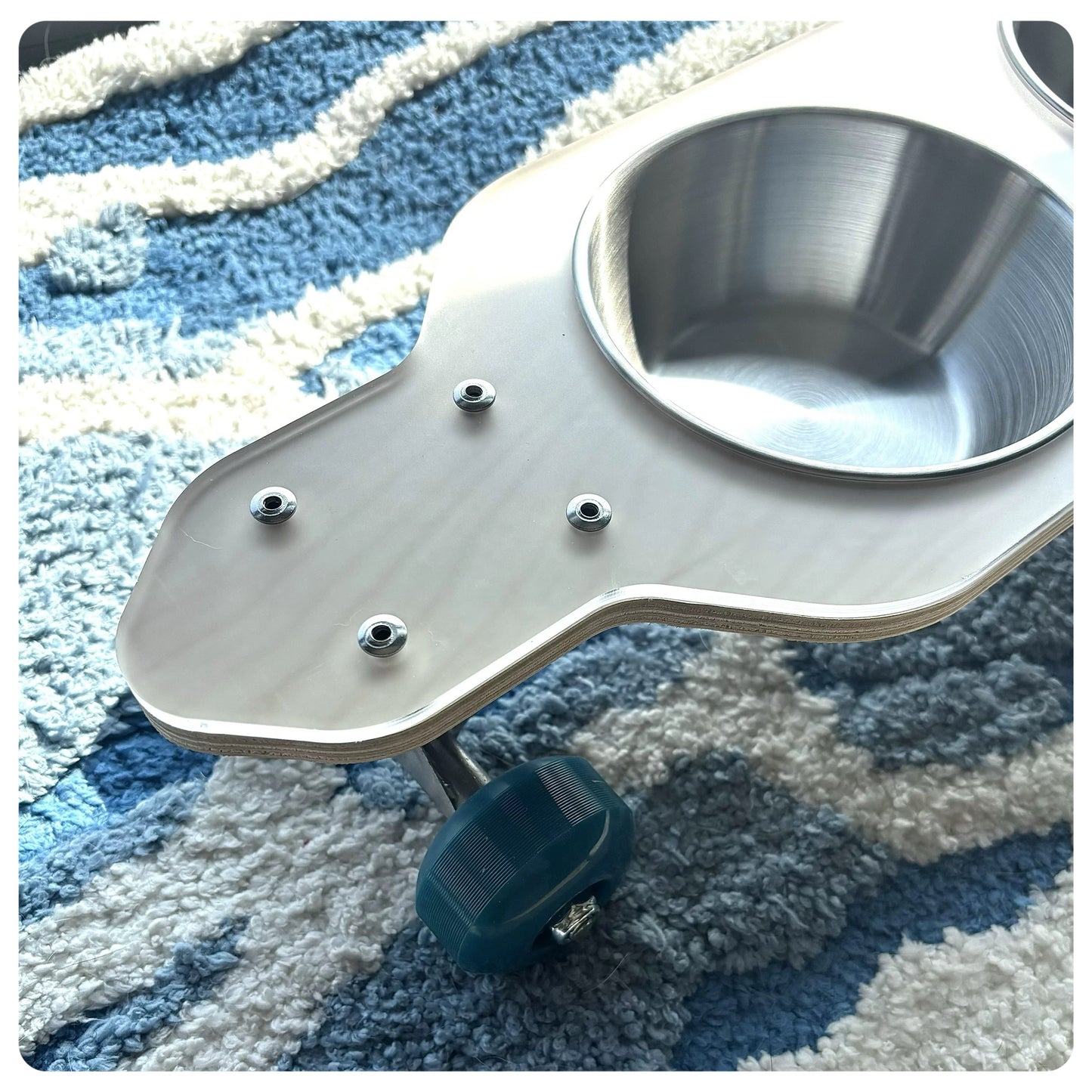 Metallic pet feeder on a textured blue and white surface