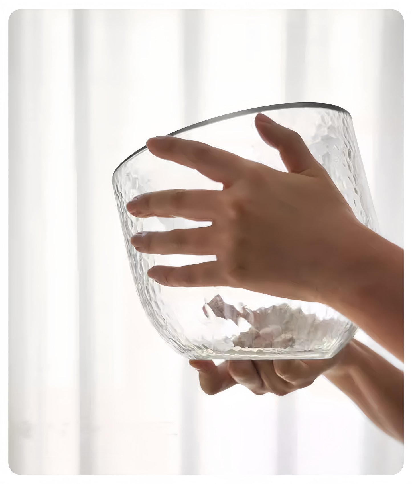 Clear glass bowl held by a hand against a white background